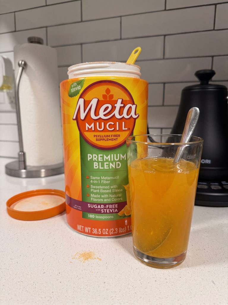 Sugar-free orange Metamucil powder stirred in a glass of water